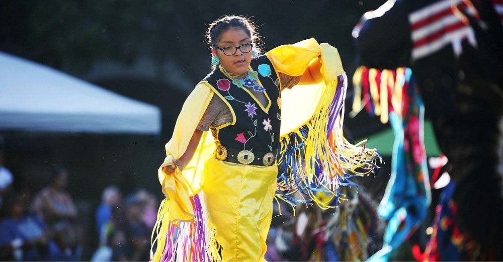 A Native American woman doing a traditional dance