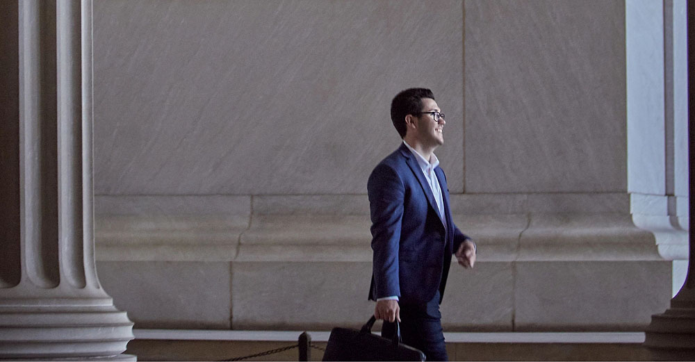 Professional man walks forward surrounded by capital architecture 