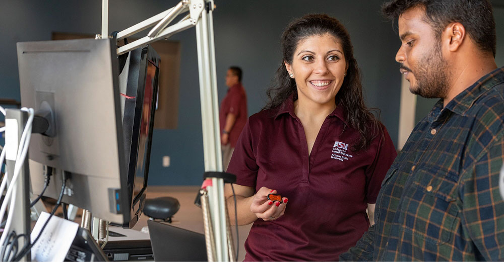ASU worker smiling while showing something on the computer to another person