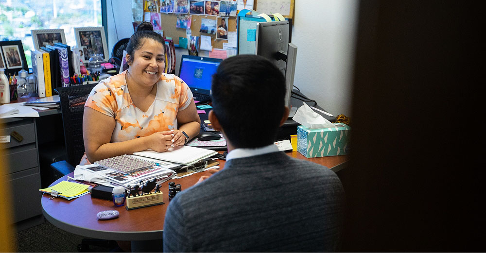 A female academic advisor having a pleasant meeting with a male student sitting across from her