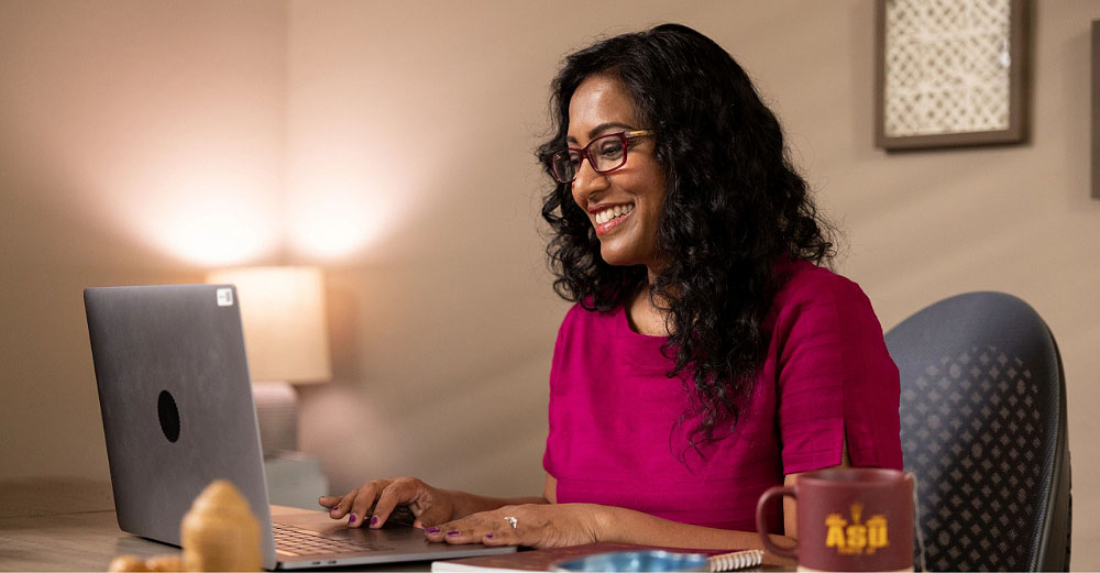 Young woman smiles and looks at a laptop computer while at home