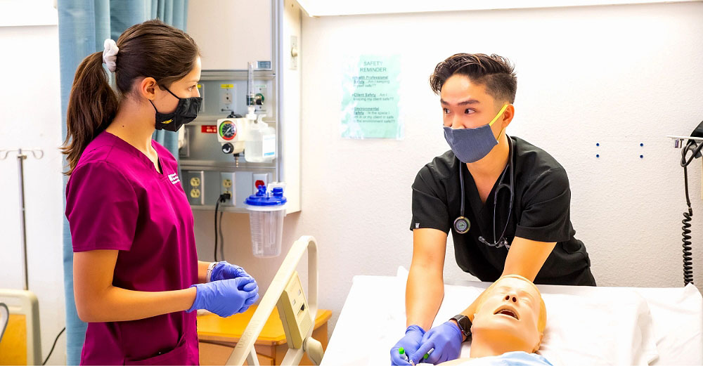 Two health students are working on a dummy patient in a hospital