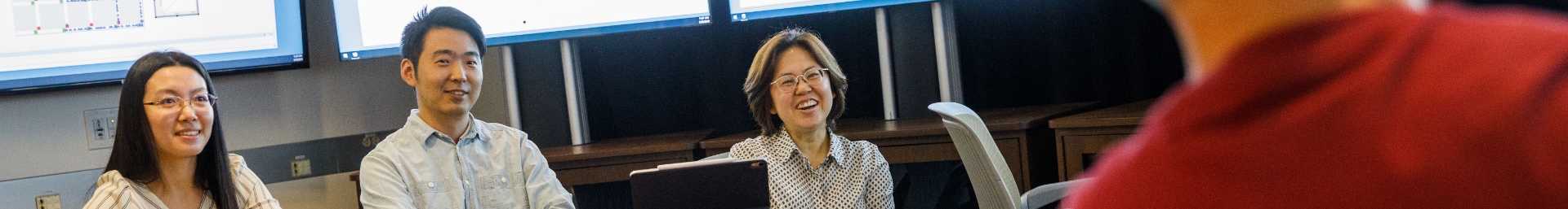 Three people sitting around a table having a ocnversation and smiling