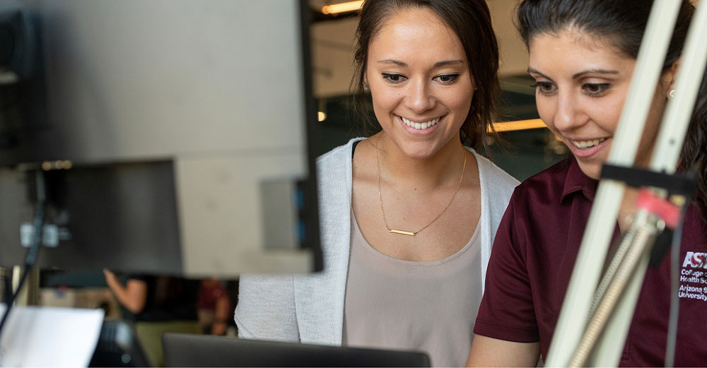 Two women smiling and studying a computer screen