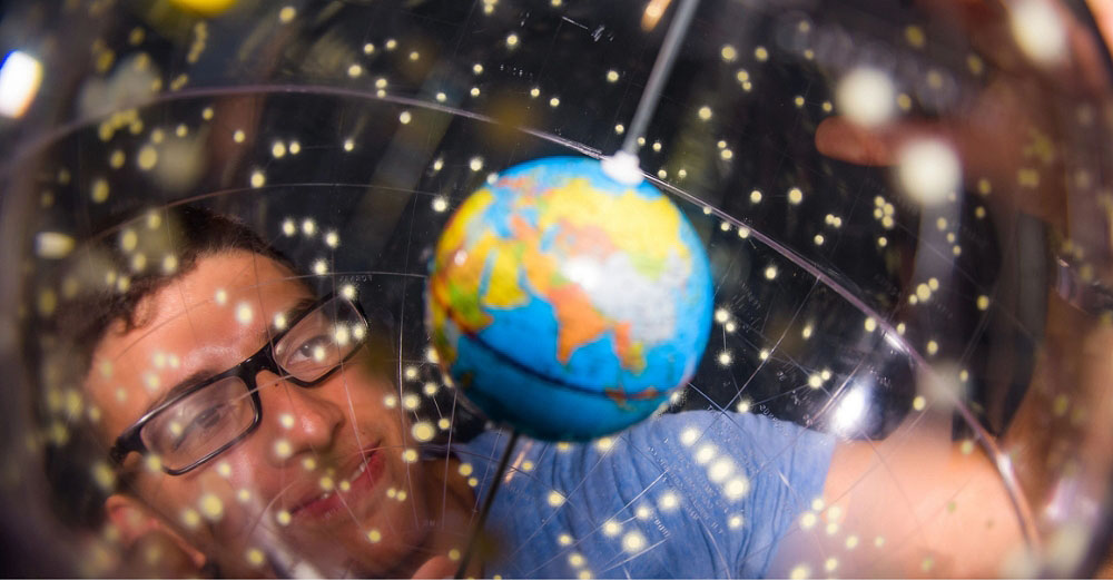 Man holding a globe and looking up at it from below
