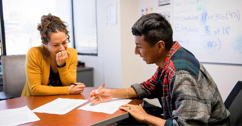 Male student discussing with female advisor about papers he has