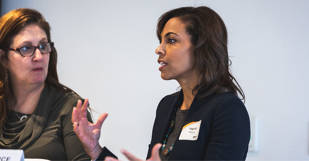 Woman talking and gesturing with her arms while an onlooker watches