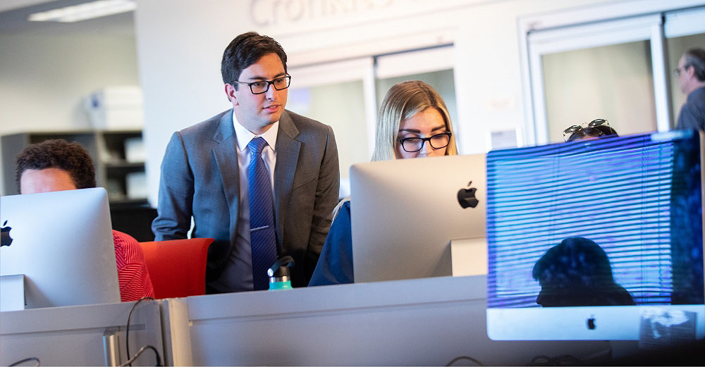 Two professional students work on a desktop computer