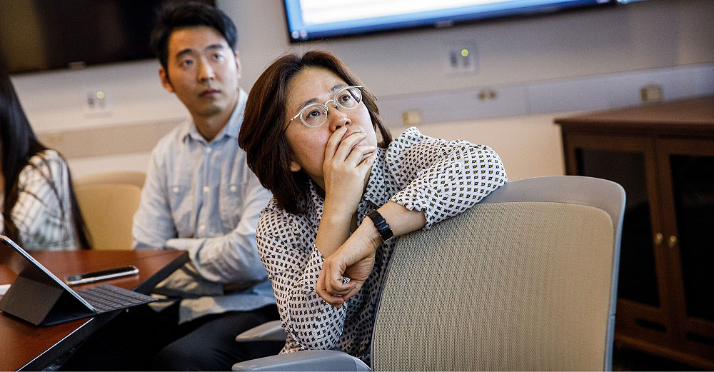 Women sits in a chair and is studying something behind her