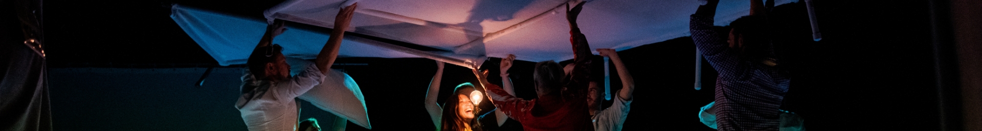 Group of people holding a stage set piece above their head and smiling