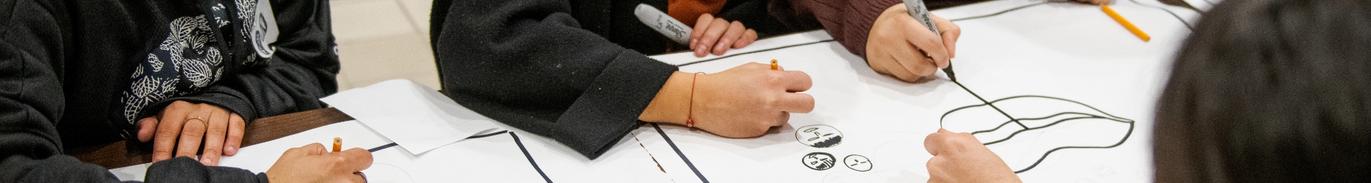 A group of people drawing on a piece of paper