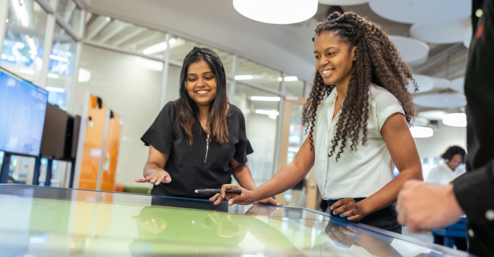 Two women working on a digital board