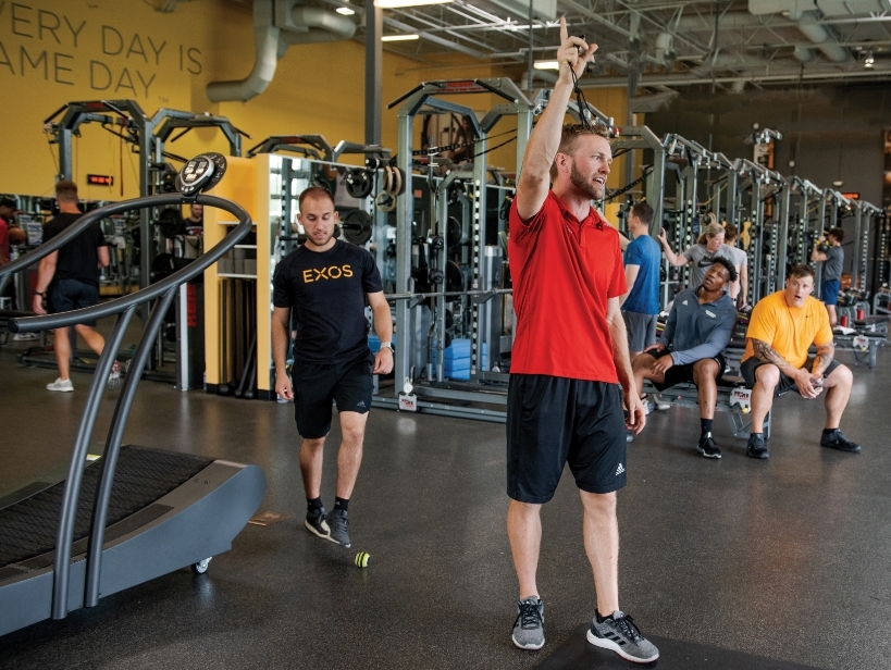 Male instructor talking to a class in a gym