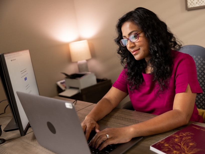 Female student smiling and typing on computer from home
