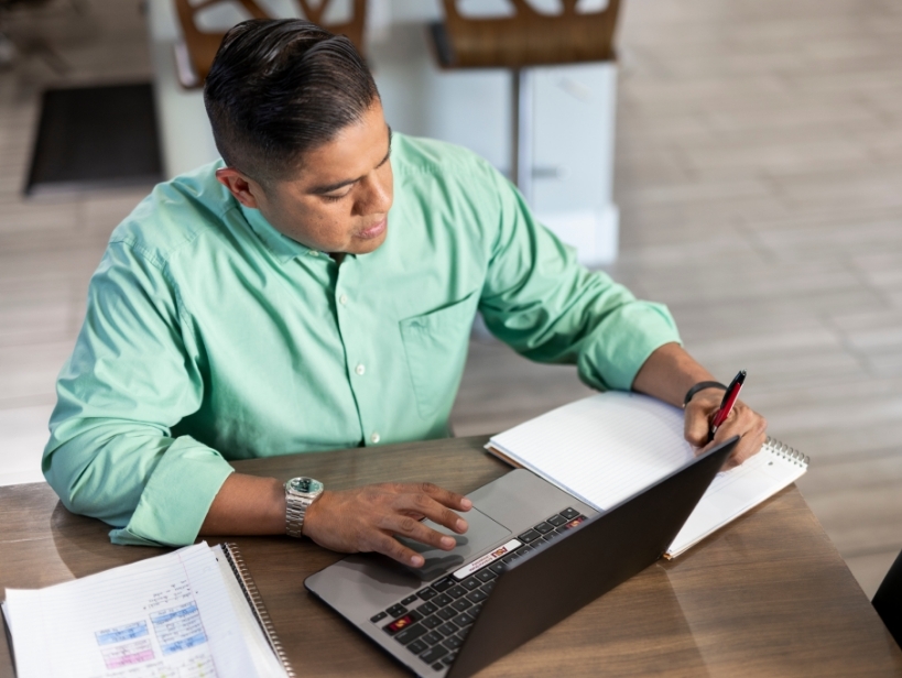 Male student working on the computer and writing